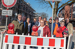 Ortstermin zum Baubeginn mit Bürgermeister Otto Steinkamp (links), Vertretern von Rat und Verwaltung, Planungsbüro, Sanierungsträger und Bauunternehmen. Links im Hintergrund der wachsende Gebäudekomplex „Wallenhorst 21“.