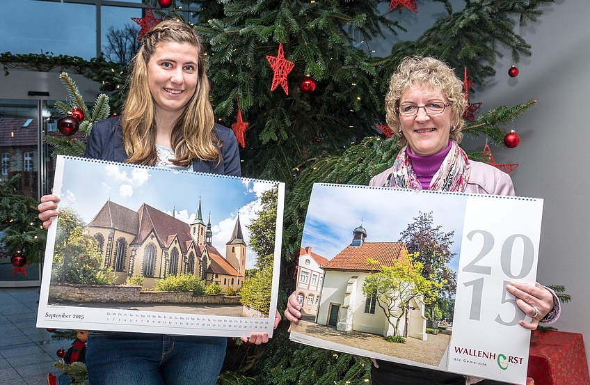 Kristina Niemann und Gisela Schawe (von links) präsentieren den Fotokalender der Gemeinde Wallenhorst, den sie an der Infotheke im Rathaus anbieten.