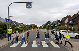 Kinder gehen in einer Gruppe über die Straße.