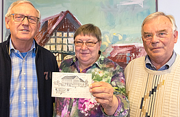 Brigitte Raddatz überreicht die historische Postkarte an Josef Torbecke (links) und Heinz Hörnschemeyer von der Archivgruppe.
