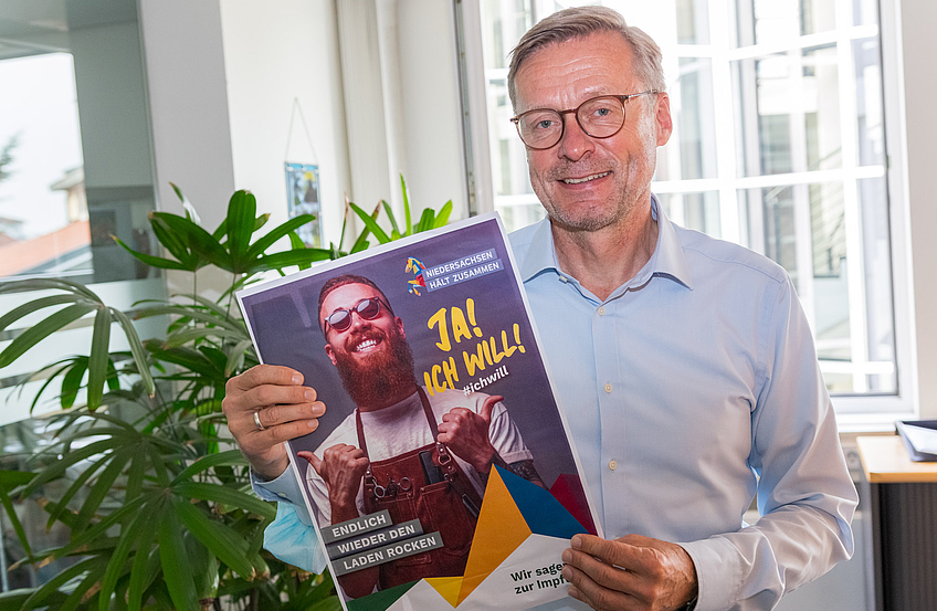 Bürgermeister Otto Steinkamp mit einem Plakat der Impfkampagne.