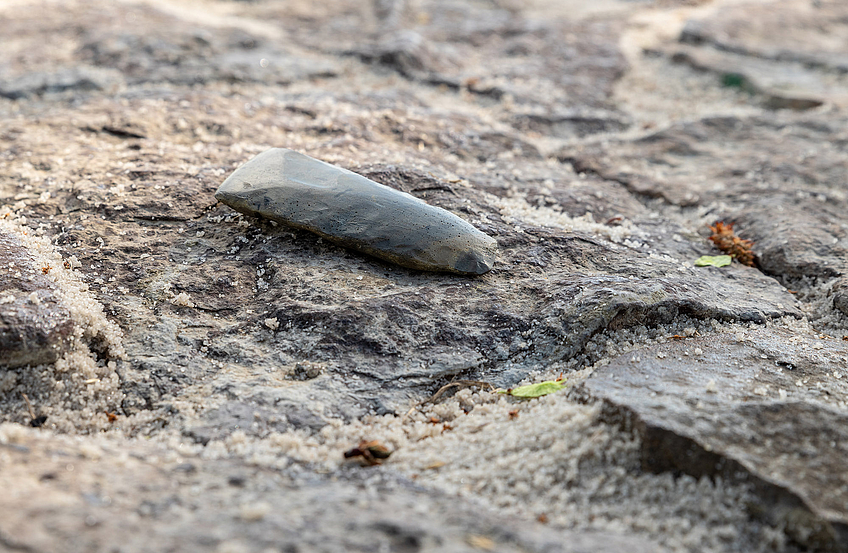 Ein Feuersteinbeil als Grabbeigabe auf dem Steinpflaster.