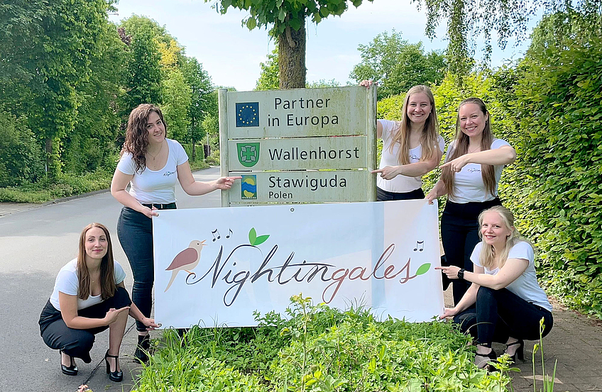 Fünf Sängerinnen der Nightingales am Hinweisschild auf die Städtepartnerschaft am Ortseingang in Rulle.