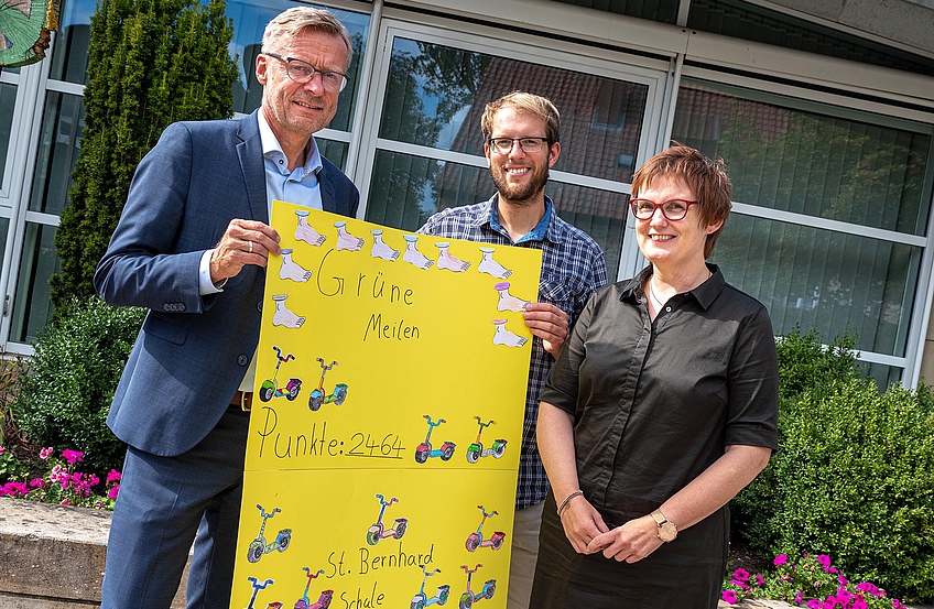 Petra Wiegmann überreicht Bürgermeister Otto Steinkamp und Klimaschutzmanager Stefan Sprenger ein Plakat mit den gesammelten „grünen Meilen“.