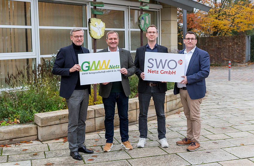 Bürgermeister Otto Steinkamp, GWW-Aufsichtsratsvorsitzender Guido Pott, GWW Netz-Geschäftsführer Florian Lüttkemöller und SWO Netz-Geschäftsführer Tino Schmelzle mit den Logos der beiden Partnerunternehmen.
