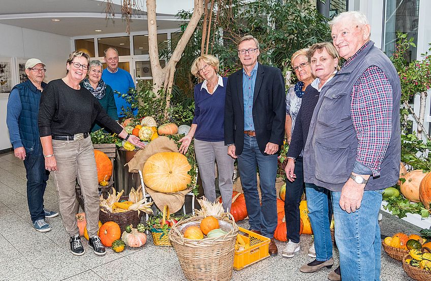Die Mitglieder des Seniorenbeirats und weitere fleißige Helfer haben im Foyer des Rathauses wieder ein „Herbstbild“ erstellt. Bürgermeister Otto Steinkamp (4. von rechts) besuchte sie beim Aufbau.